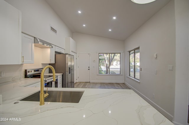 kitchen with light stone countertops, stainless steel appliances, sink, white cabinetry, and lofted ceiling