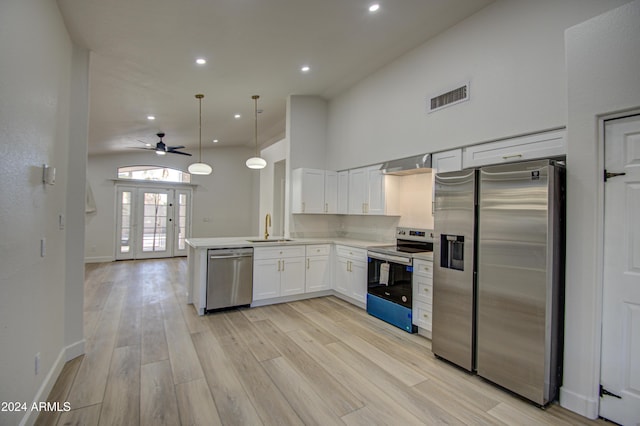 kitchen with pendant lighting, white cabinets, light wood-type flooring, appliances with stainless steel finishes, and kitchen peninsula