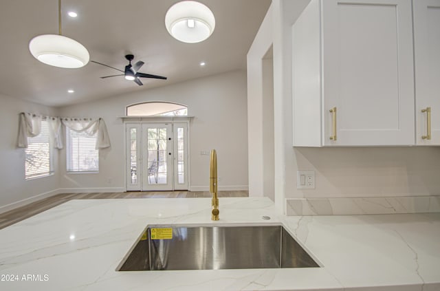 kitchen with light stone counters, lofted ceiling, and sink