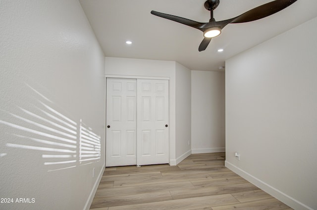 unfurnished bedroom with ceiling fan, light hardwood / wood-style floors, and a closet