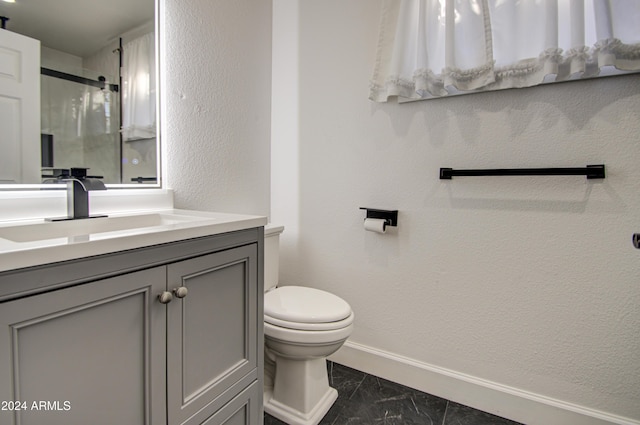 bathroom featuring a shower with door, vanity, and toilet