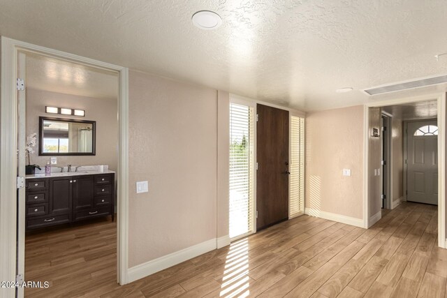 entryway with a textured ceiling, light wood-type flooring, and sink