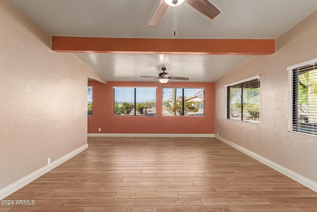 spare room with light wood-type flooring, beam ceiling, ceiling fan, and a healthy amount of sunlight