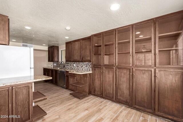 kitchen featuring white refrigerator, dishwasher, light wood-type flooring, and a textured ceiling