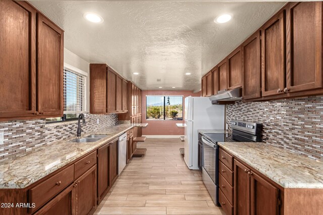 kitchen with stainless steel appliances, backsplash, light hardwood / wood-style floors, and sink