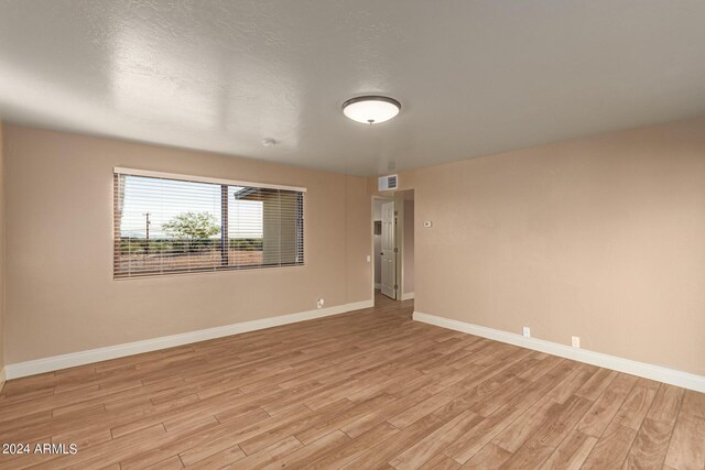 unfurnished room with light hardwood / wood-style flooring and a textured ceiling