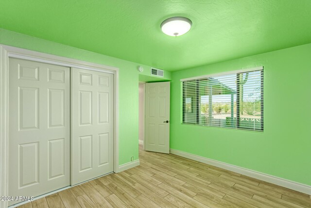 unfurnished bedroom featuring a closet and light hardwood / wood-style floors