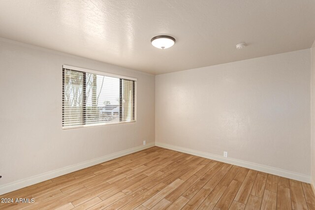 empty room featuring a textured ceiling and light hardwood / wood-style flooring