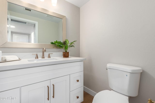 bathroom with visible vents, baseboards, toilet, and vanity