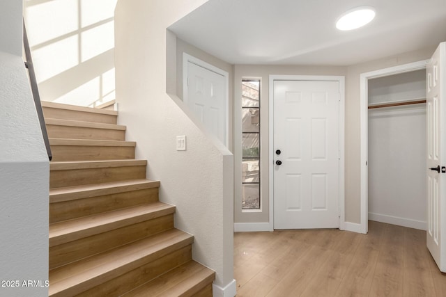 entrance foyer with stairs, baseboards, and light wood finished floors