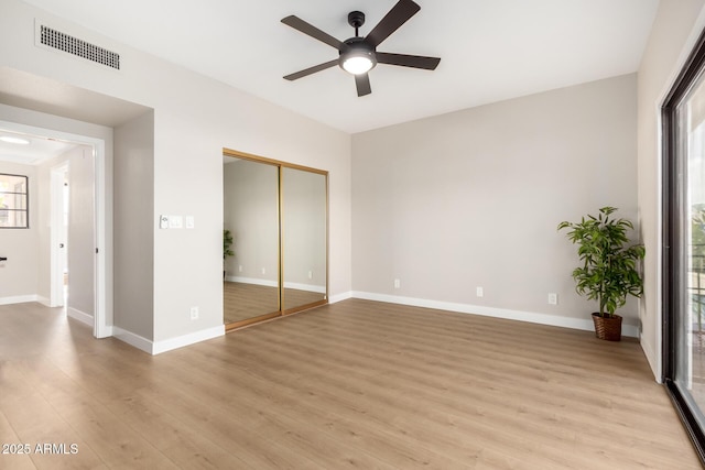 unfurnished bedroom with light wood-type flooring, visible vents, a ceiling fan, a closet, and baseboards