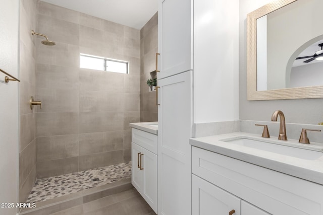 bathroom with tiled shower, vanity, and a ceiling fan