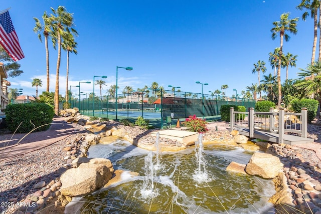 view of home's community with a tennis court and fence