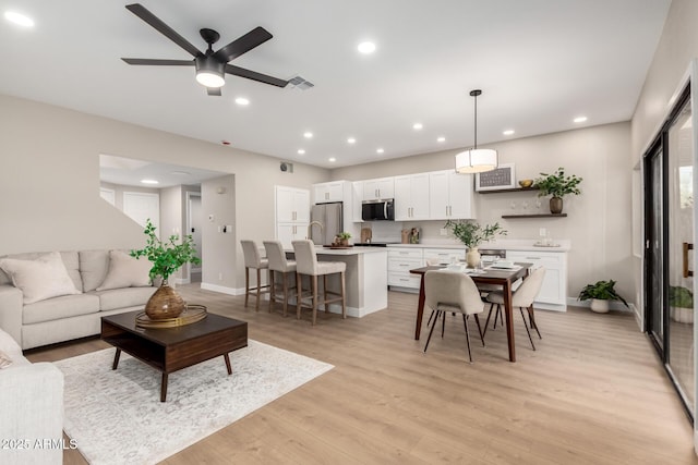 living room with recessed lighting, visible vents, light wood-style flooring, and a ceiling fan