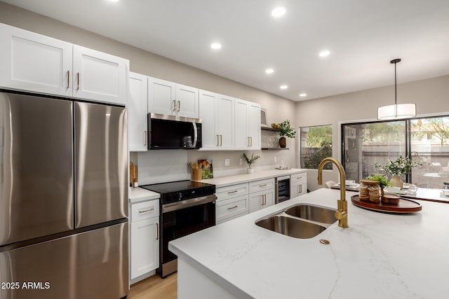 kitchen with pendant lighting, open shelves, a sink, appliances with stainless steel finishes, and white cabinets