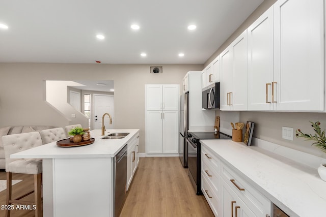 kitchen with a breakfast bar area, an island with sink, recessed lighting, a sink, and appliances with stainless steel finishes