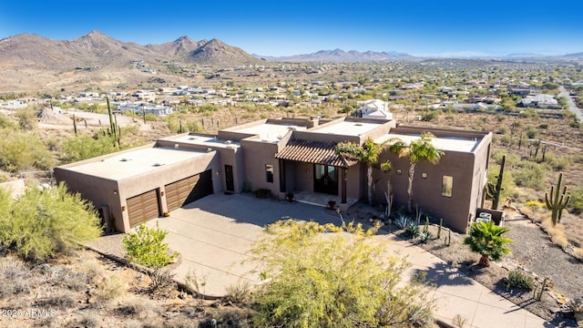 southwest-style home featuring driveway, an attached garage, a mountain view, and stucco siding