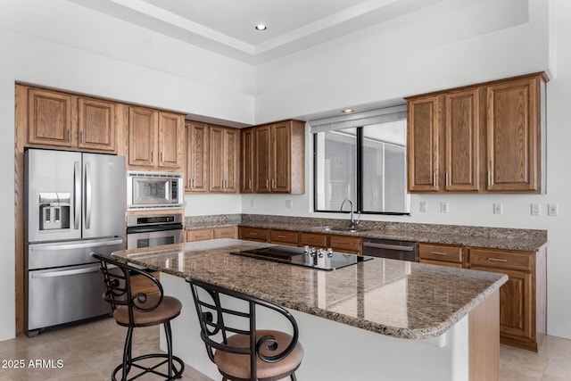 kitchen featuring stainless steel appliances, brown cabinetry, and a sink