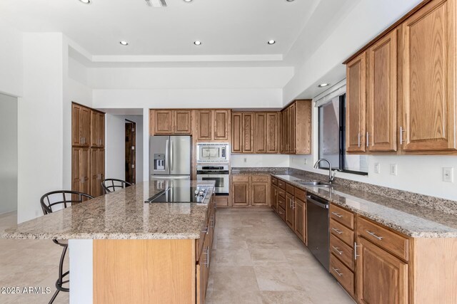 kitchen featuring light stone countertops, a kitchen bar, stainless steel appliances, and a sink