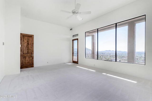 carpeted empty room with ceiling fan and a mountain view