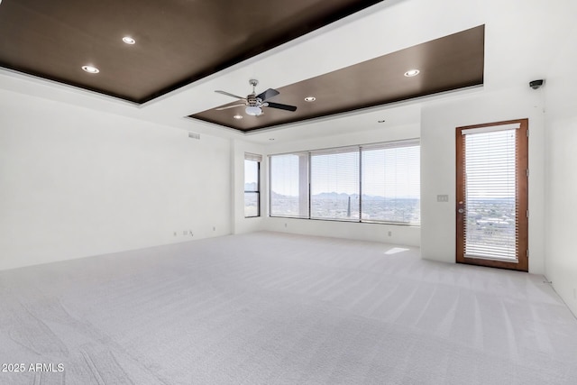 unfurnished room with a tray ceiling, recessed lighting, visible vents, light carpet, and ceiling fan