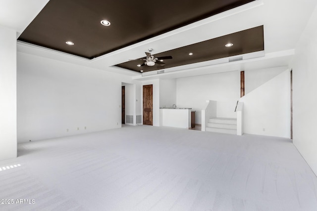 unfurnished living room with carpet floors, a tray ceiling, recessed lighting, visible vents, and a ceiling fan