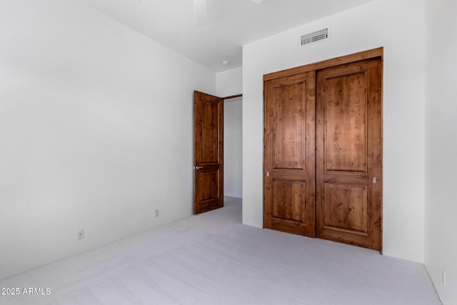 unfurnished bedroom with carpet, visible vents, and ceiling fan