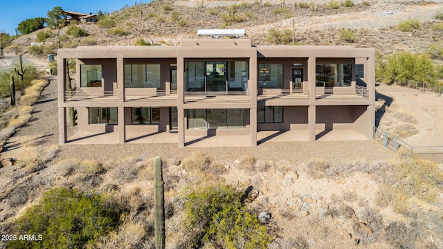 rear view of house with a patio area, a balcony, and stucco siding