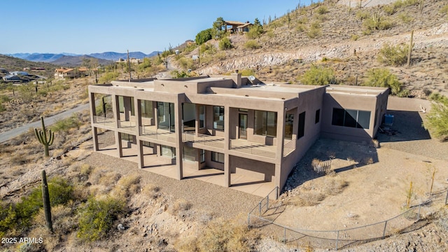 back of house featuring a mountain view, a patio, a balcony, and stucco siding