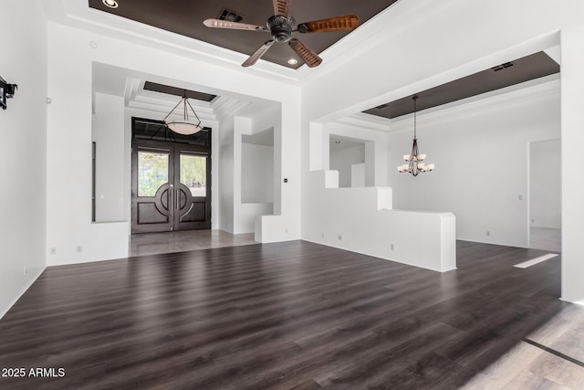 empty room featuring a raised ceiling, crown molding, and wood finished floors