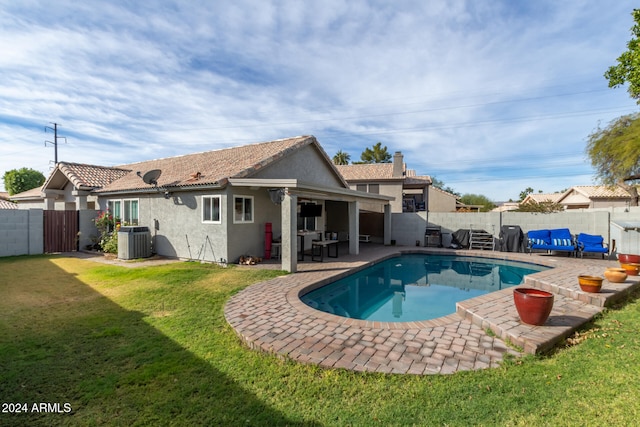 back of property with a lawn, a patio area, a fenced in pool, and central air condition unit