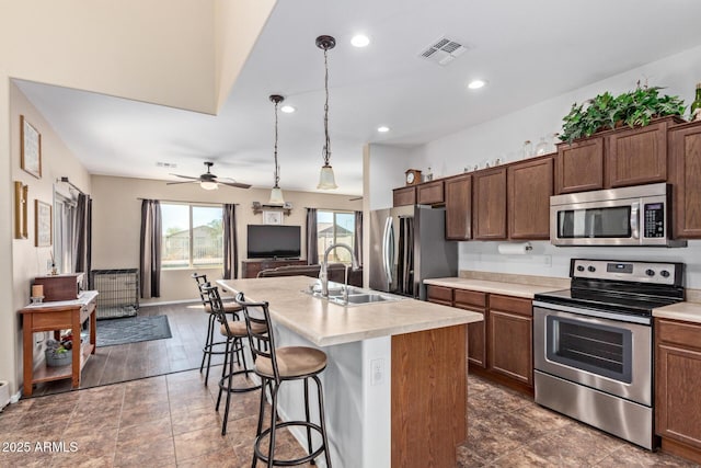 kitchen featuring a sink, visible vents, open floor plan, light countertops, and appliances with stainless steel finishes