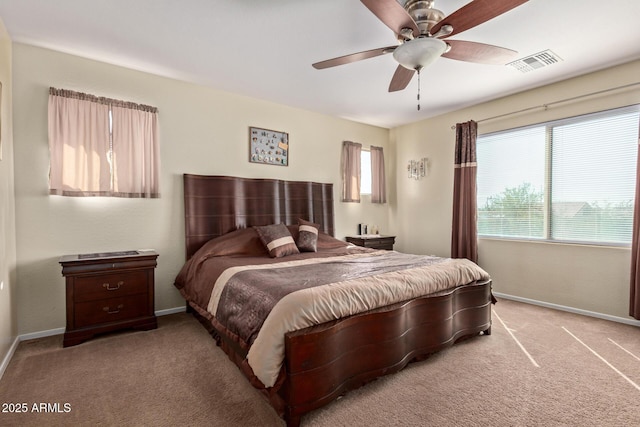 carpeted bedroom with baseboards, multiple windows, visible vents, and ceiling fan