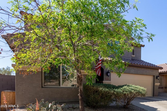 obstructed view of property with driveway, a garage, a tile roof, fence, and stucco siding