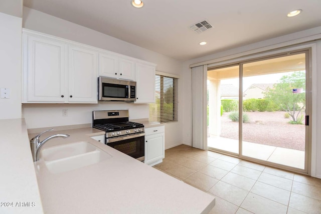 kitchen with appliances with stainless steel finishes, white cabinetry, a healthy amount of sunlight, and sink