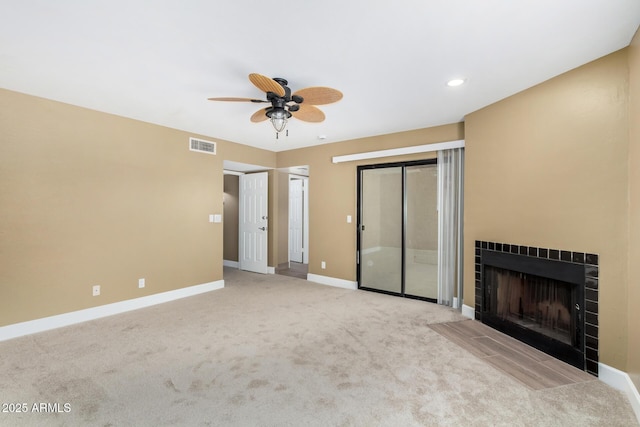 unfurnished living room with visible vents, baseboards, a tiled fireplace, ceiling fan, and carpet flooring