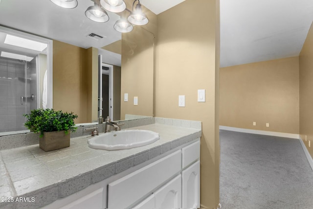 bathroom with visible vents, a tile shower, vanity, and baseboards