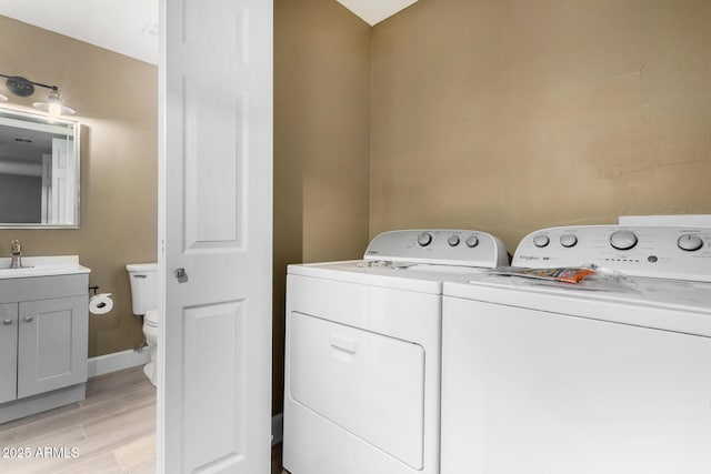 laundry area featuring a sink, light wood-style flooring, baseboards, and washer and dryer