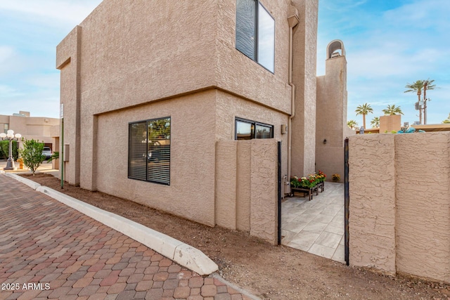 view of side of home with a patio, fence, and stucco siding