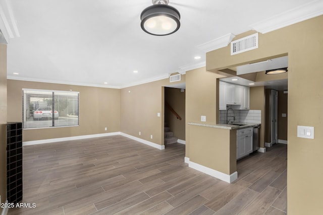 kitchen with light wood-style flooring, backsplash, a sink, and visible vents