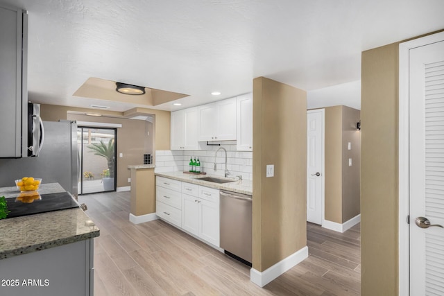 kitchen with tasteful backsplash, wood tiled floor, appliances with stainless steel finishes, and a sink