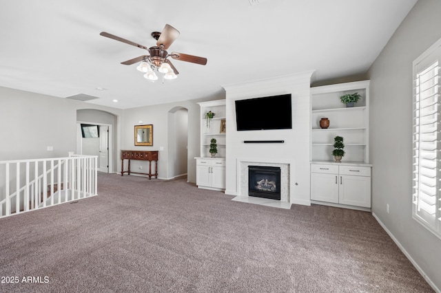 824 E Chelsea Dr, San Tan Valley, AZ 85140 - unfurnished living room with carpet flooring, a fireplace with flush hearth, plenty of natural light, arched walkways, and ceiling fan