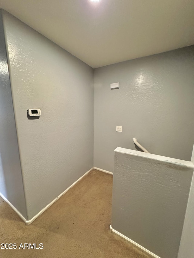 corridor with an upstairs landing, baseboards, and carpet floors