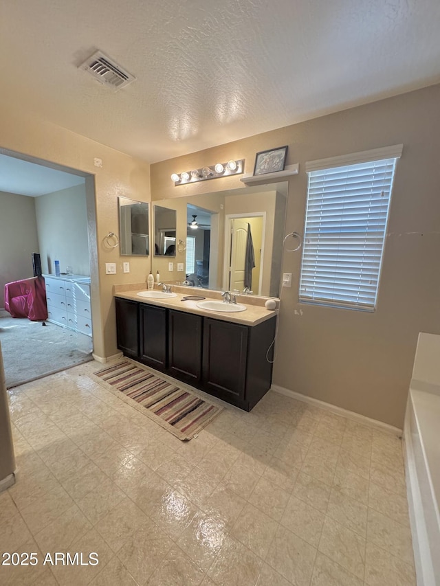 full bath featuring double vanity, baseboards, visible vents, and a sink