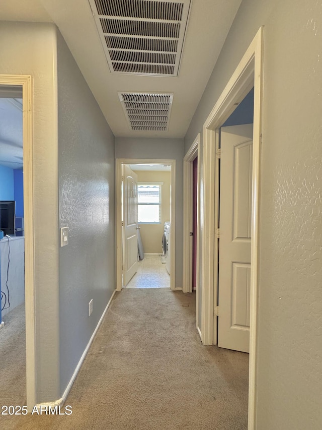 hallway featuring visible vents, baseboards, carpet flooring, and a textured wall