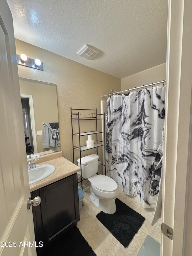 bathroom featuring vanity, visible vents, a textured ceiling, toilet, and a textured wall