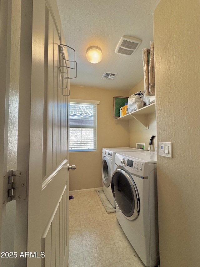 washroom with washer and dryer, visible vents, a textured ceiling, and laundry area