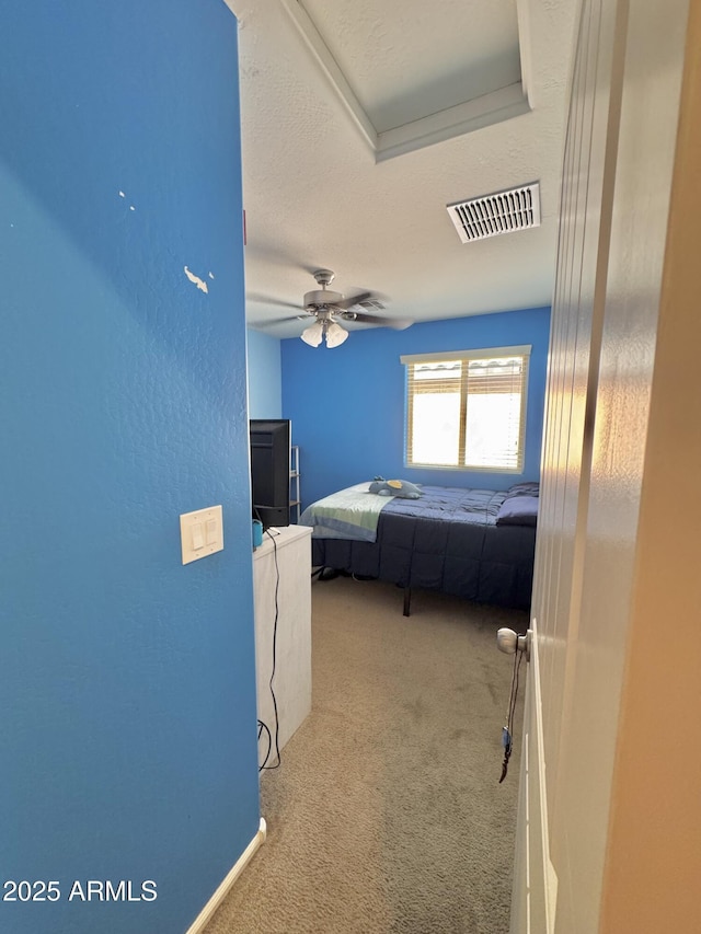 carpeted bedroom with visible vents, a textured ceiling, and a ceiling fan