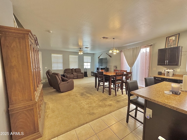 living area with light tile patterned floors, visible vents, ceiling fan, a textured ceiling, and light colored carpet