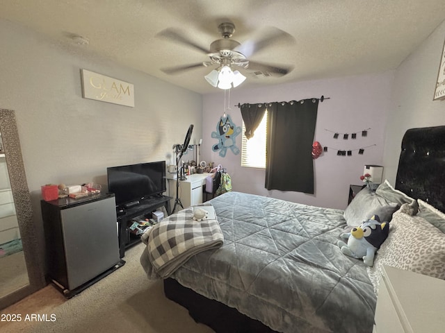 carpeted bedroom featuring ceiling fan, freestanding refrigerator, and a textured ceiling